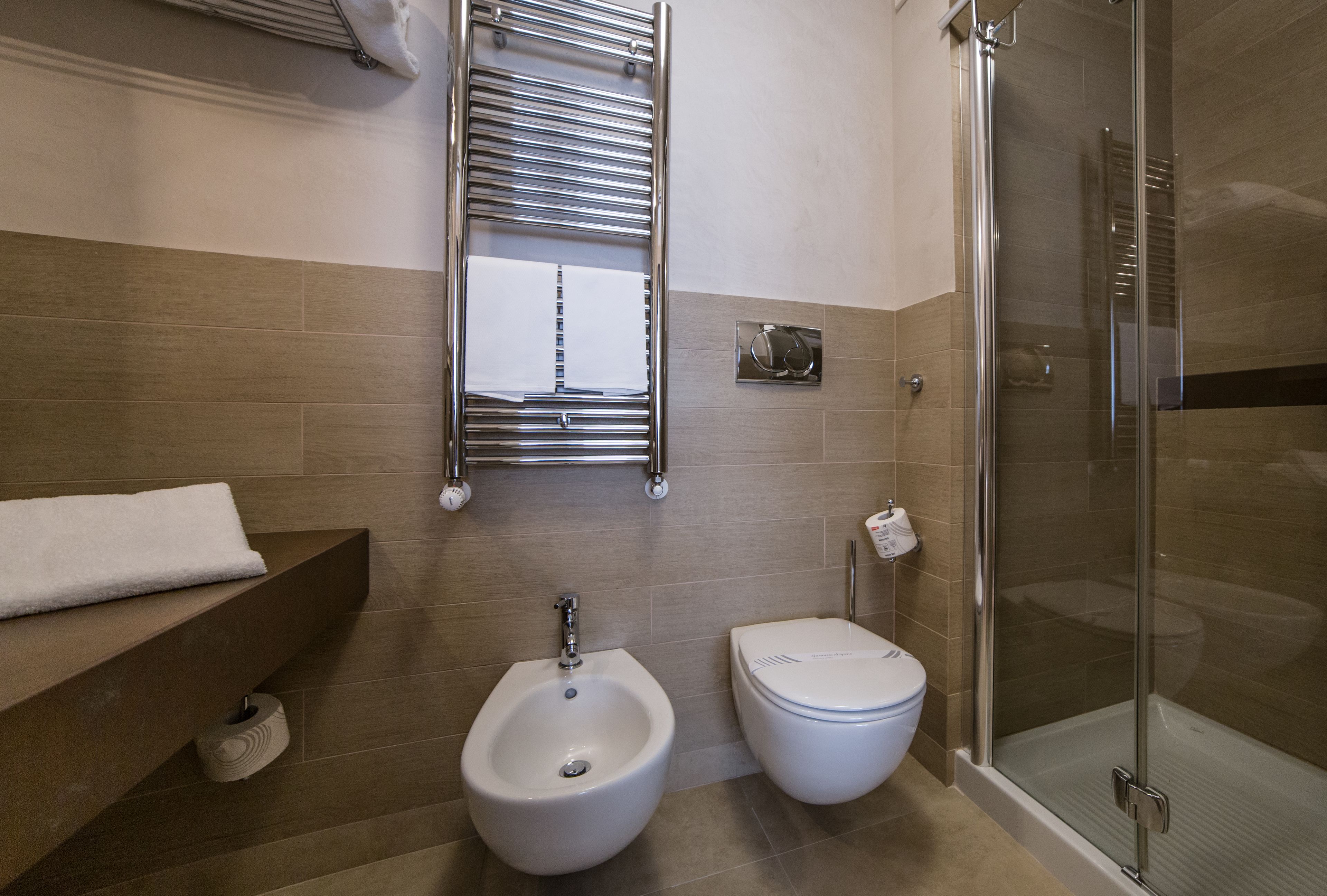 Un baño moderno con bidé, inodoro y cabina de ducha de vidrio.