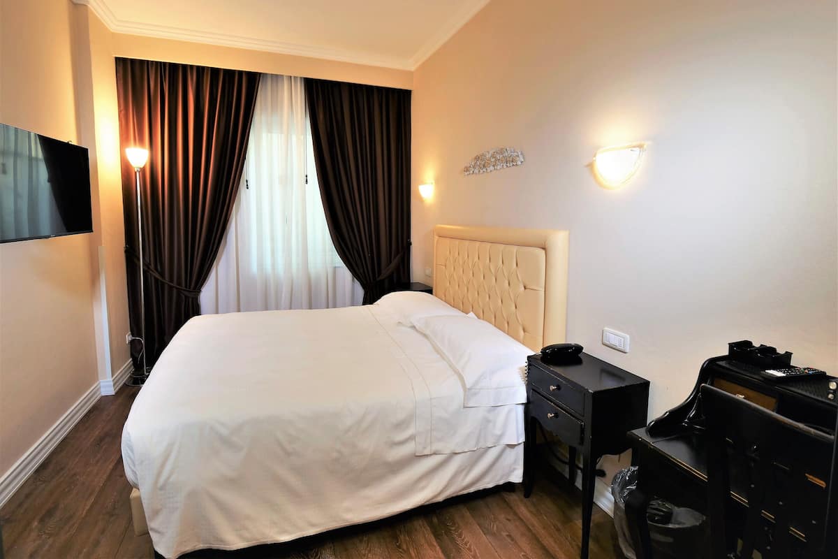 Une chambre d’hôtel équipée d’un lit, d’un bureau avec un ordinateur et d’un téléviseur fixé au mur.