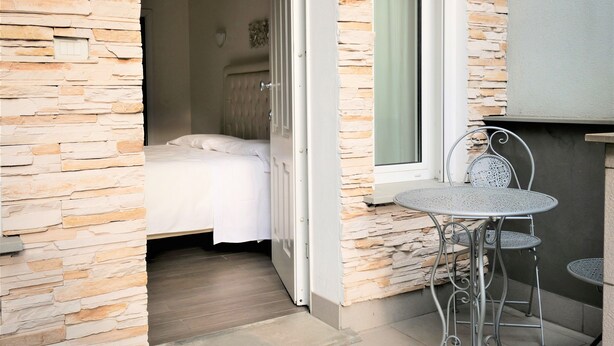 A room with a bed, a door leading to a balcony, and a small table with chairs. - Hotel Patavium (Padova)