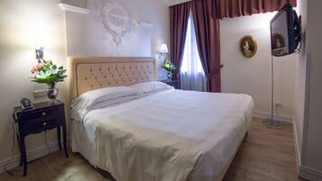 A neatly made bed with a headboard, a bedside table with a lamp, and a wall-mounted TV.
