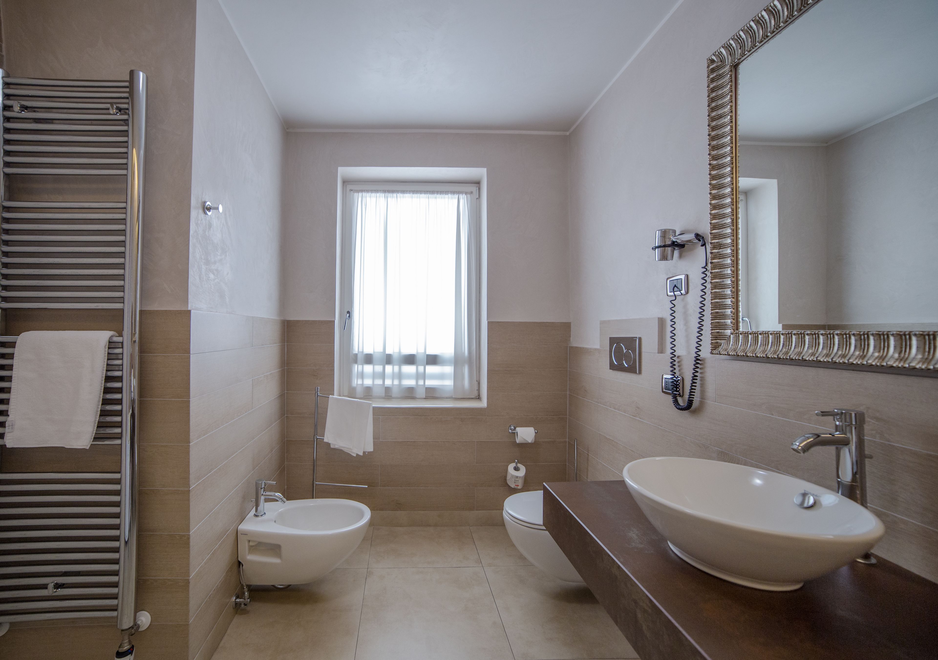 Un baño moderno con bidé, lavabo, espejo y toallero.