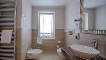 Un baño moderno con bidé, lavabo, espejo y toallero.
