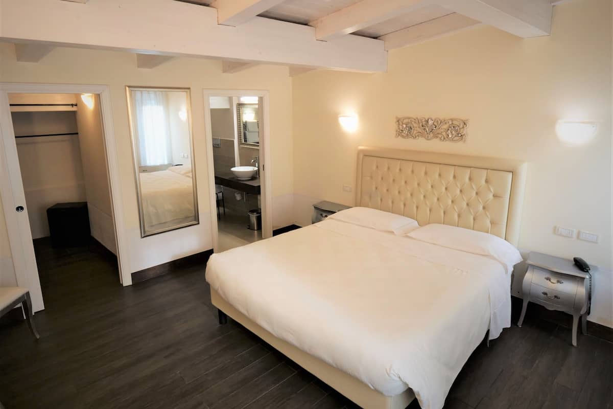 Une chambre à coucher avec un grand lit, une table de chevet, un miroir et une armoire.