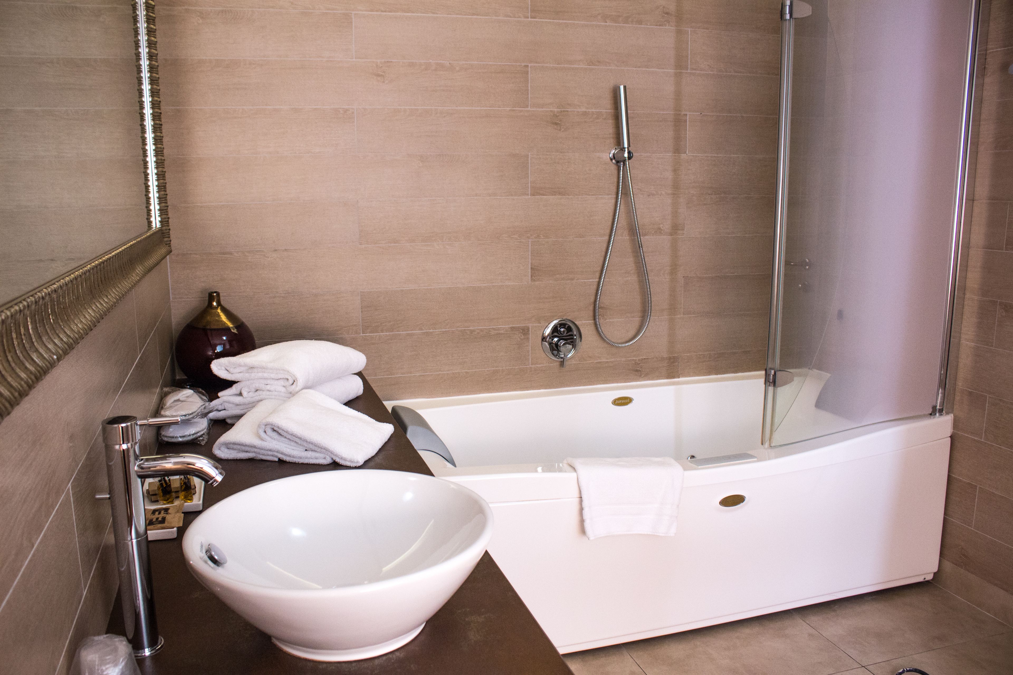 A modern bathroom with a bathtub, a glass-enclosed shower, a large white sink, and neatly folded towels.