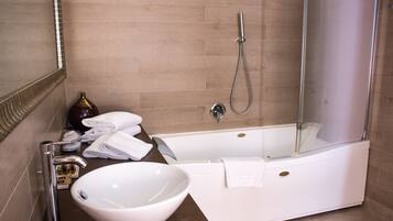 A modern bathroom with a bathtub, a glass-enclosed shower, a large white sink, and neatly folded towels.