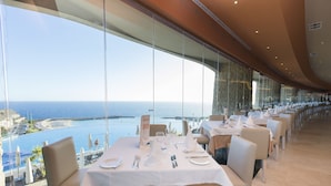 A restaurant with tables set for dining, overlooking a coastal view. - Gloria Palace Royal Hotel & Spa (Mogan)