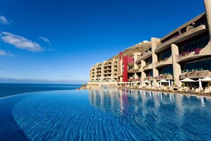 Un hotel con una amplia piscina infinita, vistas a la playa y un diseño arquitectónico moderno.
