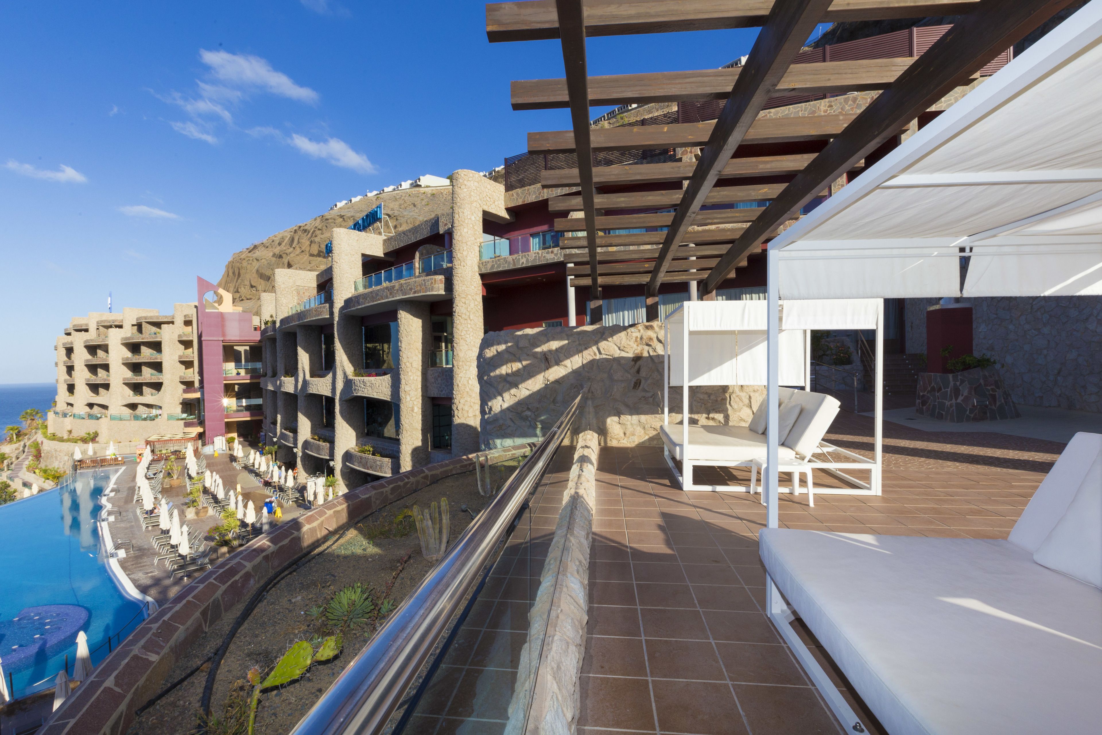 Un resort con piscina, asientos al aire libre y vista al océano.