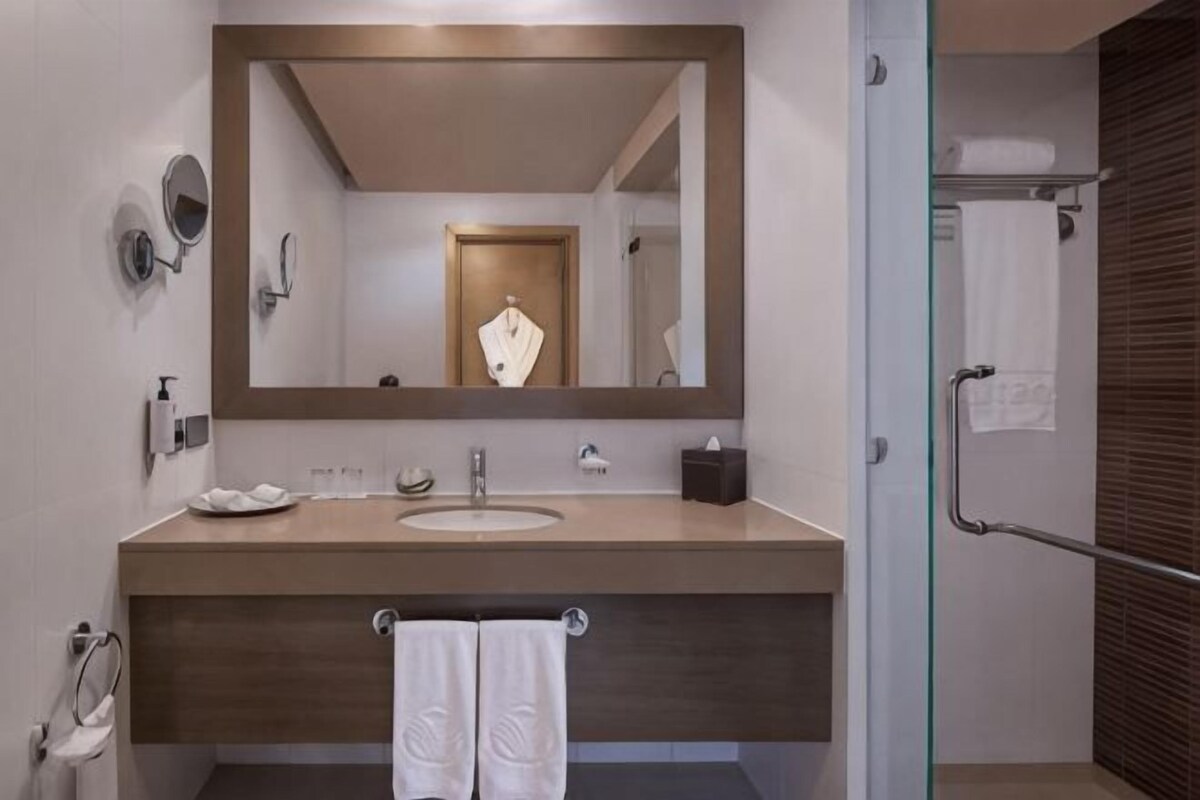 A modern bathroom with a large mirror, a sink, and a glass shower enclosure.