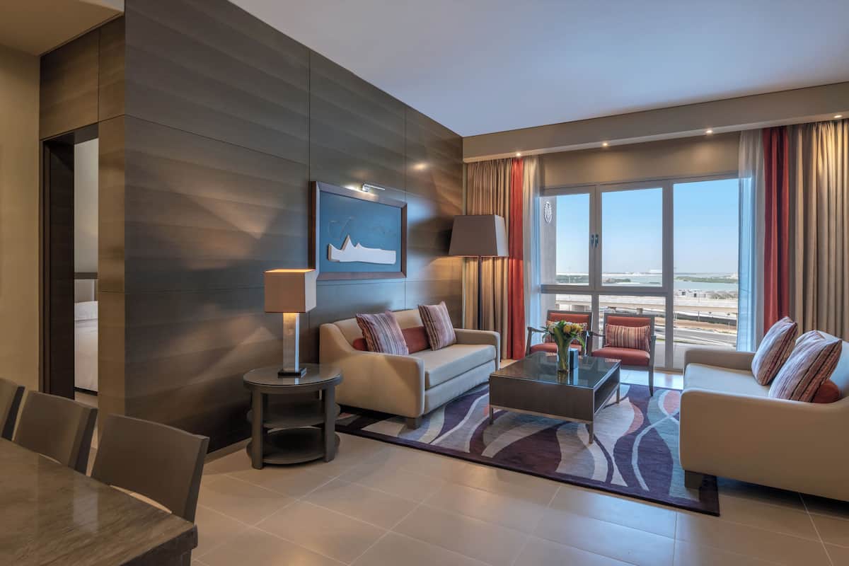 A modern living room with a sofa, armchairs, a coffee table, and a dining area.