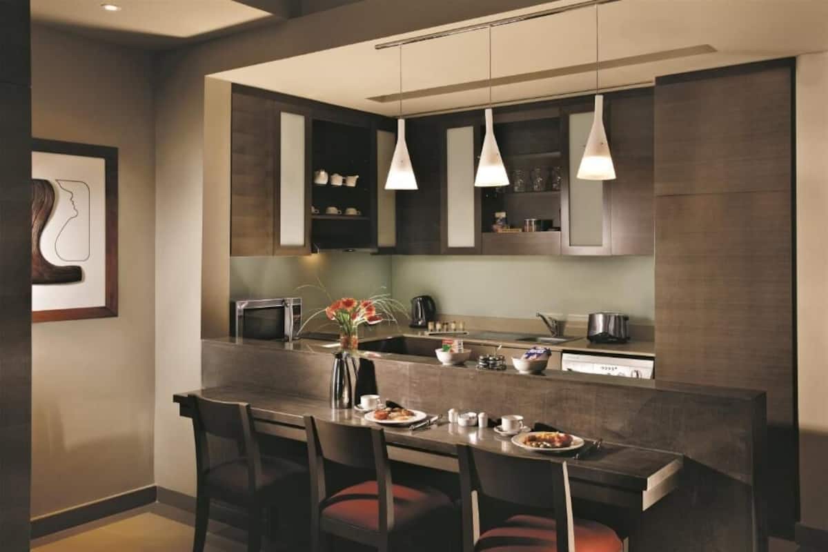 A modern kitchen with a central island, pendant lighting, and a dining area with chairs.