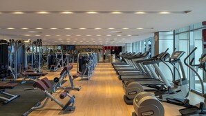 Een sportschool met diverse fitnessapparaten, waaronder loopbanden en krachtapparaten, gerangschikt in rijen.