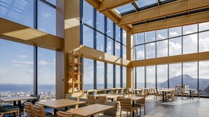 Spaziosa sala da pranzo con soffitti alti e ampie finestre che offrono vista sulla città.