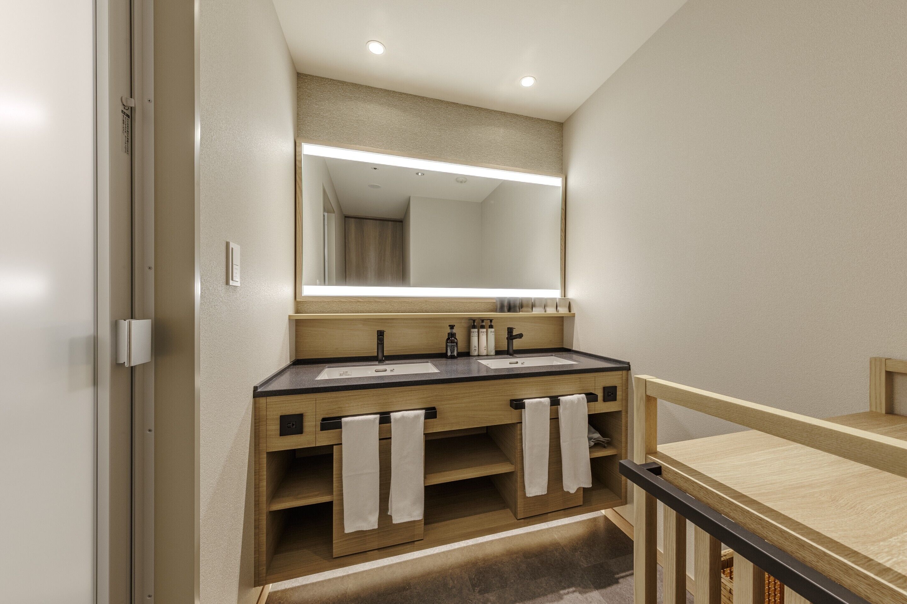 A modern bathroom with a wooden vanity, two sinks, and a large mirror.