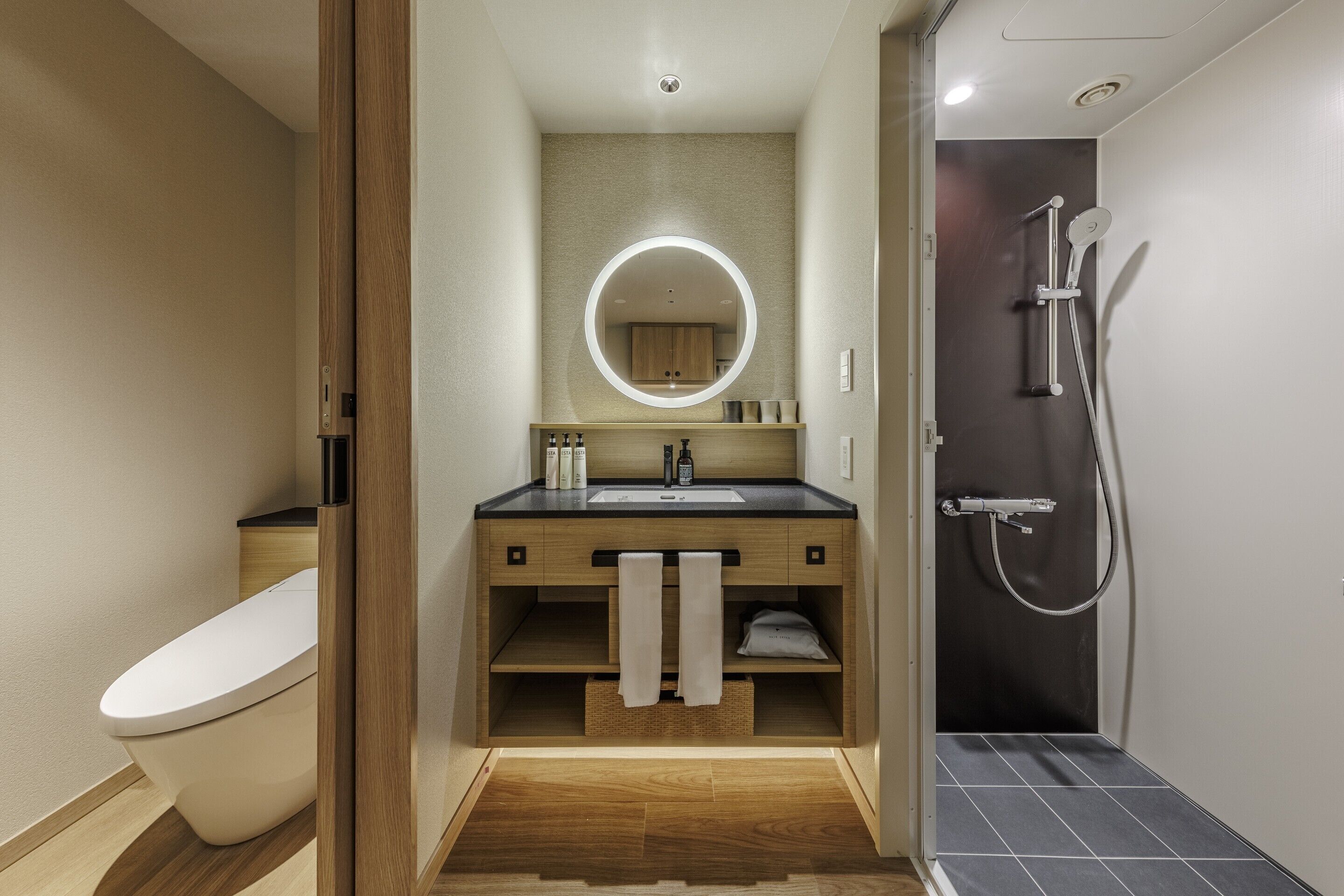 A modern bathroom with a toilet, sink, mirror, and shower.