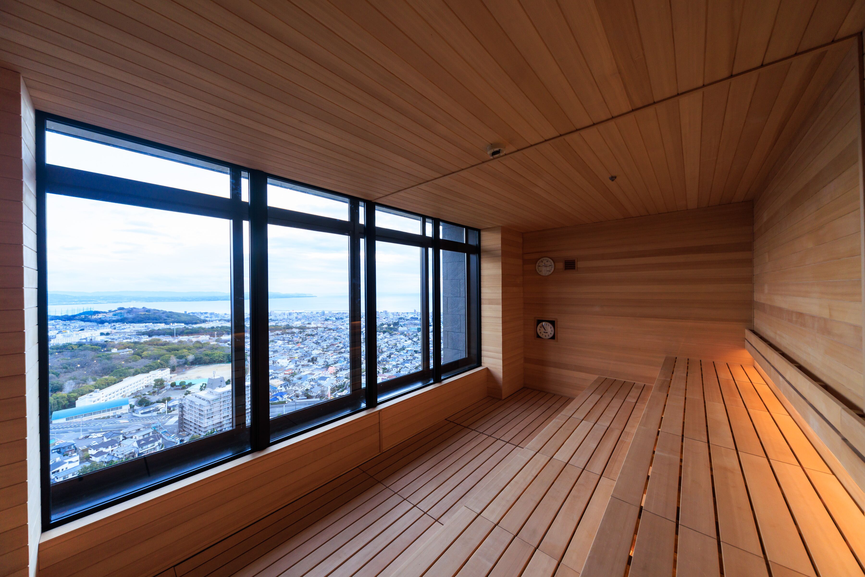 A room with large windows, wooden flooring, and a clock on the wall.