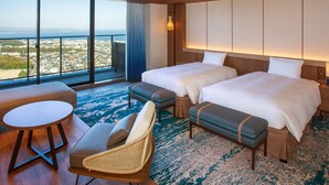 A hotel room with two beds, a sofa, a small table, and a view of a cityscape through large windows. - Beppu SUGINOI HOTEL（ORIX HOTELS & RESORTS） (Beppu)
