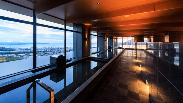 A modern hotel corridor with large windows offering a city view. - Beppu SUGINOI HOTEL（ORIX HOTELS & RESORTS） (Beppu)