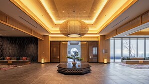 A spacious lobby with a central wooden reception desk, a large hanging light fixture, and a view through the glass doors. - Beppu SUGINOI HOTEL（ORIX HOTELS & RESORTS） (Beppu)