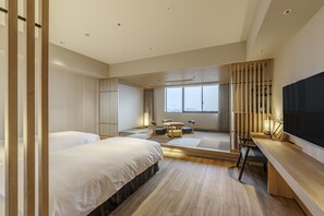 A modern hotel room with two beds, a desk, a TV, and a large window.