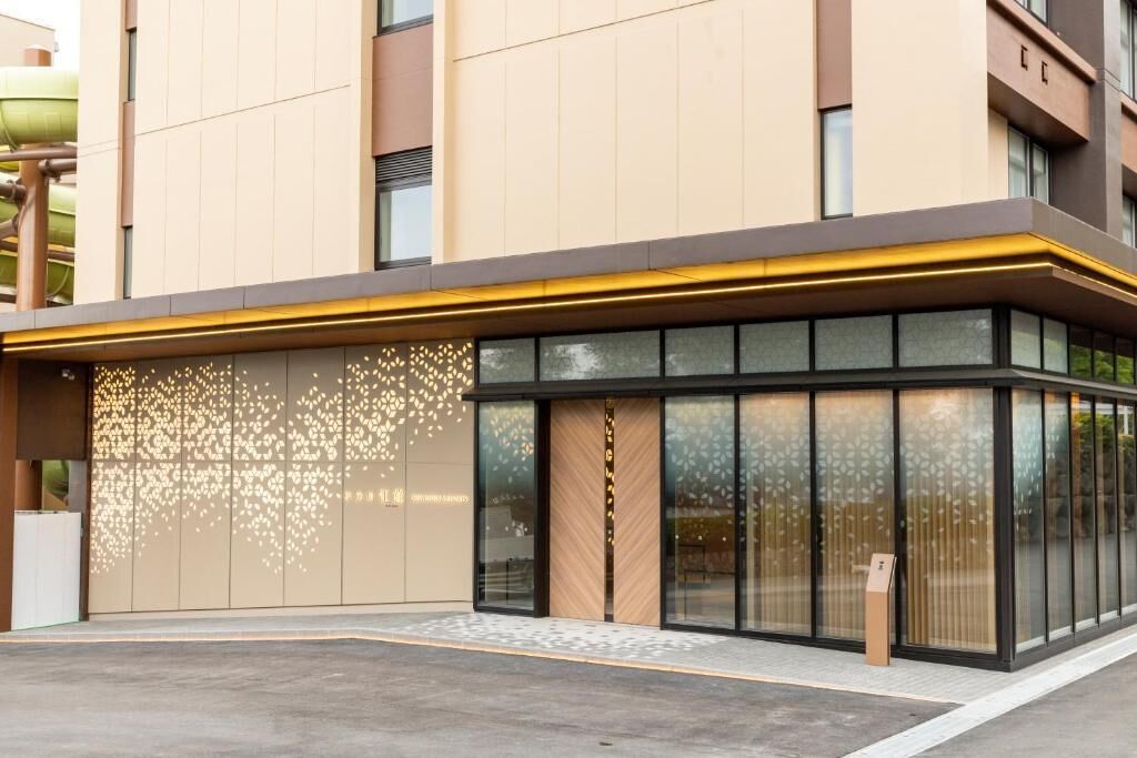 A modern building with a glass facade, a wooden door, and a signboard.