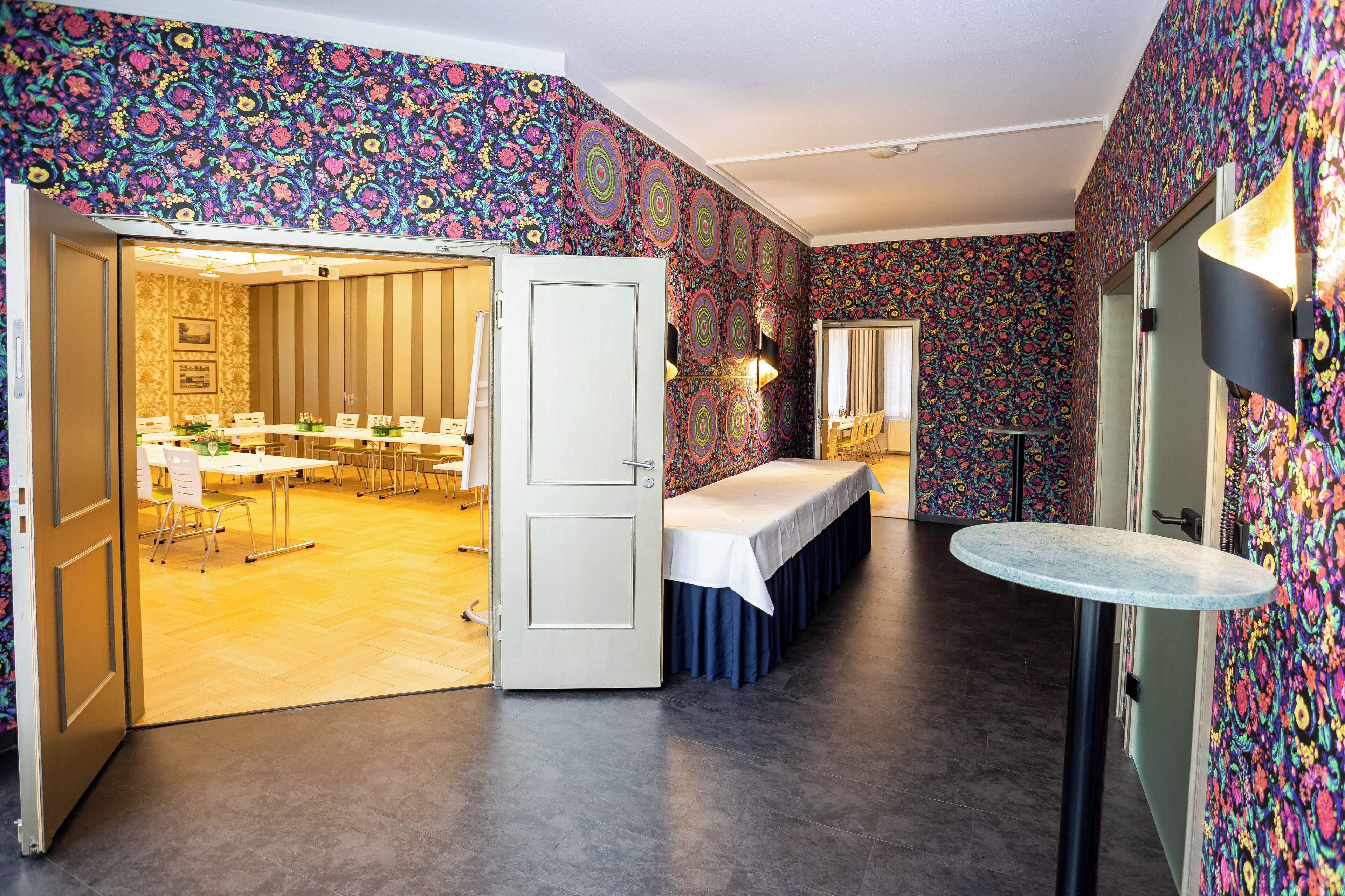 Une salle de conférence équipée d’une grande table, de chaises et d’une porte donnant sur une autre pièce.