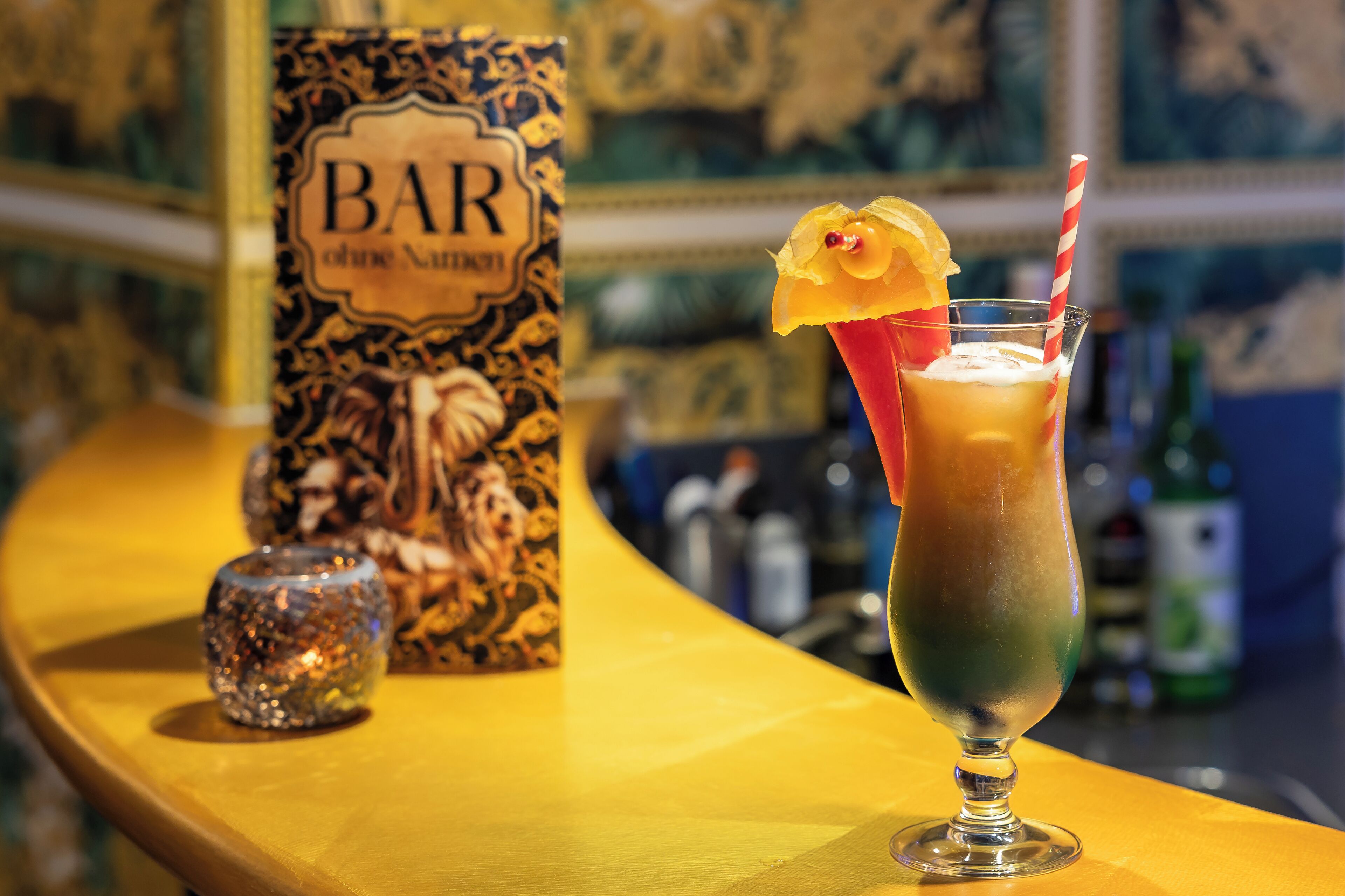 A bar setting with a cocktail in a glass, a decorative bottle, and a bar sign.