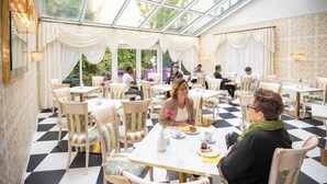 A restaurant with checkered flooring, white and gold decor, and a glass ceiling. - Hotel Alexandra (Plauen)