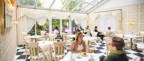 Un restaurante con suelo de cuadros, decoración blanca y dorada, y techo de cristal.