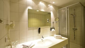 A bathroom with a sink, mirror, and shower.