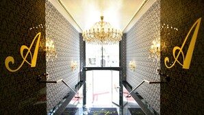 A grand entrance with a chandelier, two illuminated 'A' signs, and a view of the street outside. - Hotel Alexandra (Plauen)