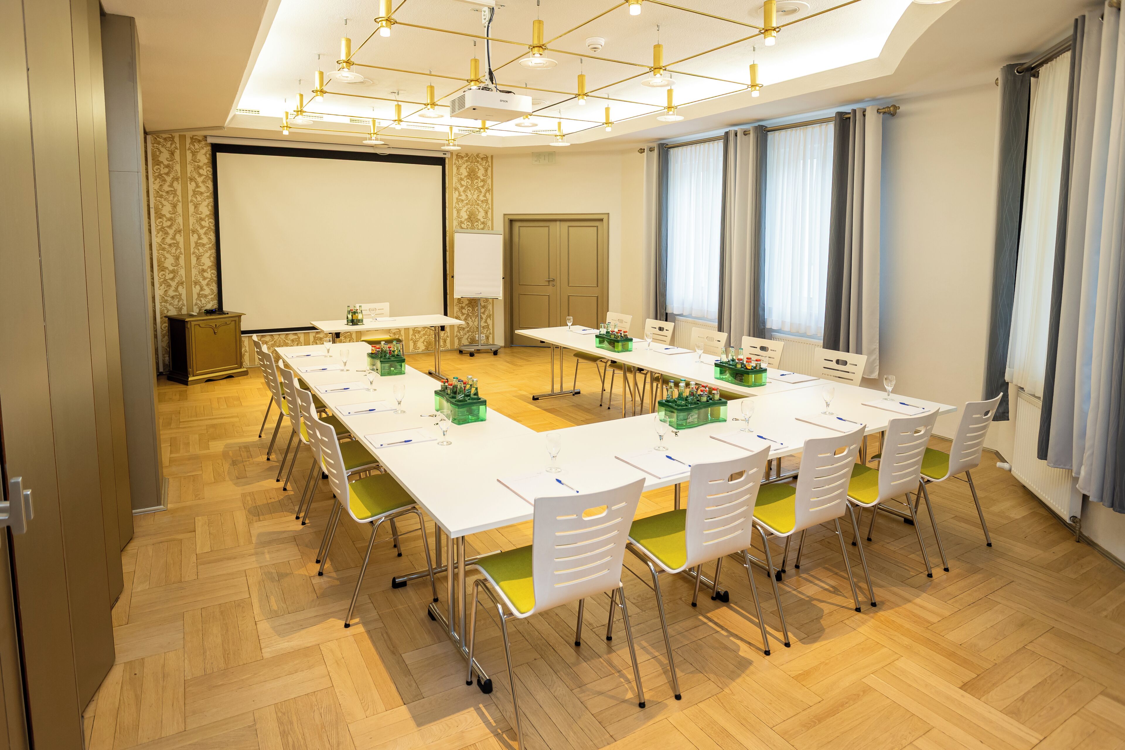 Una sala conferenze con un lungo tavolo, sedie, uno schermo per proiettore e una lavagna.