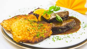 A plate of food with a golden-brown fried item, a dark meat with sauce, and orange slices.