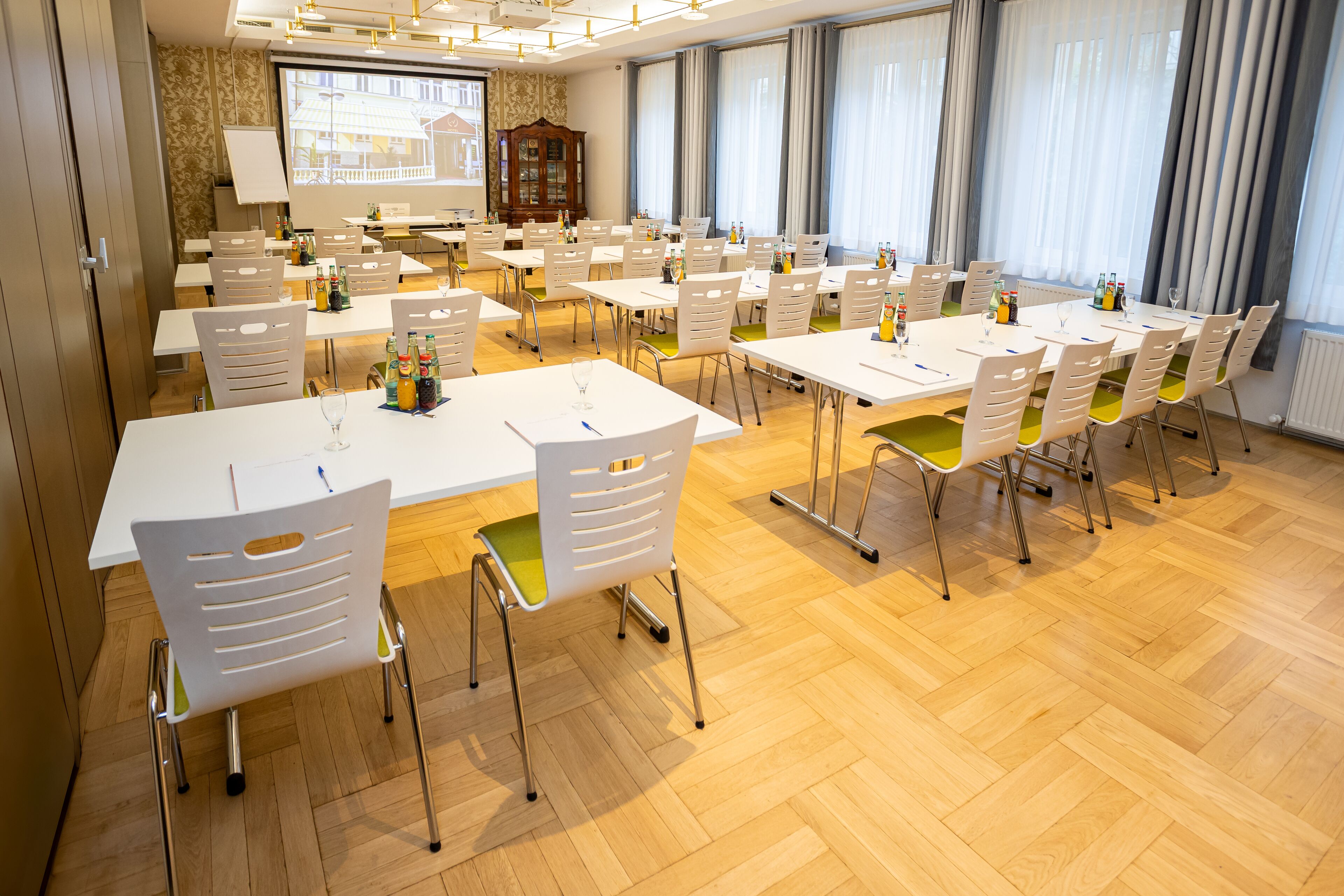 Un salón de conferencias con varias mesas y sillas, equipado con botellas de agua y vasos.