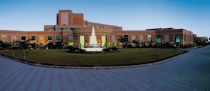 Stunning building with a central entrance and two wings, set amidst a beautifully manicured lawn and paved walkway.