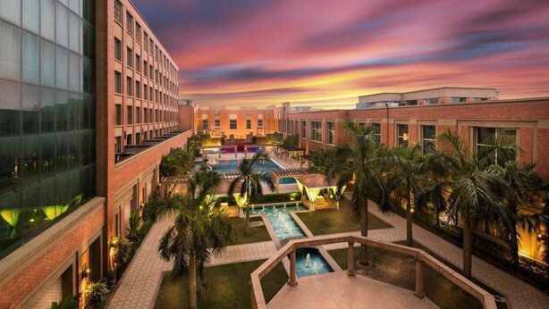 A hotel courtyard with a swimming pool, palm trees, and a sunset view.