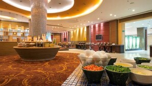 A hotel lobby with a reception desk, buffet area, and seating arrangements.