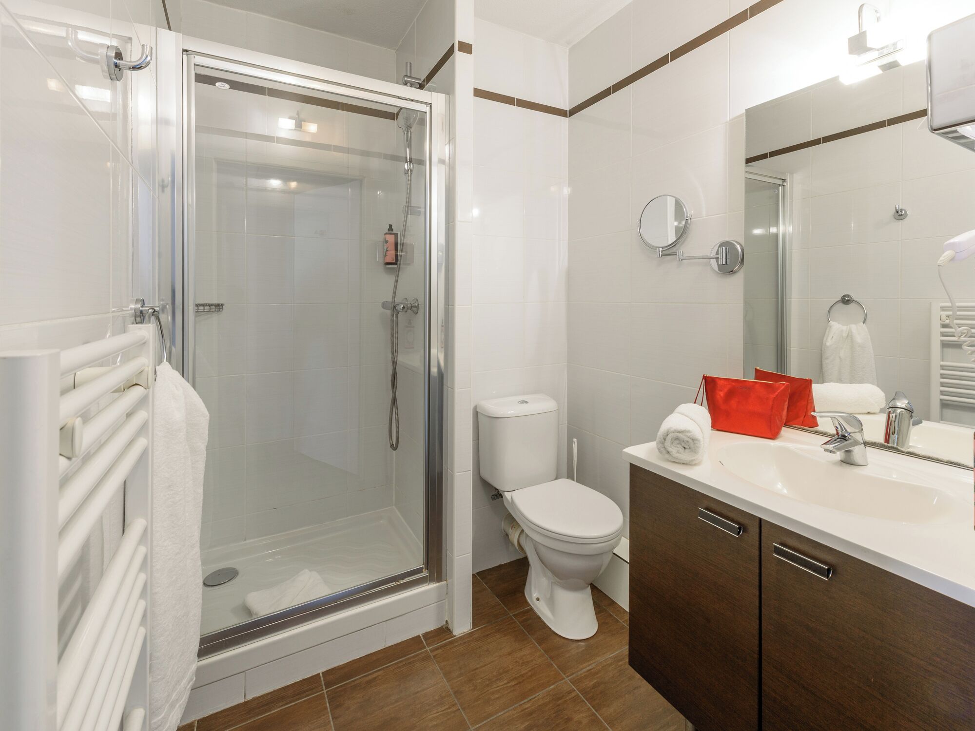 Een moderne badkamer met een douchecabine van glas, een wit toilet en een wastafel met spiegel.