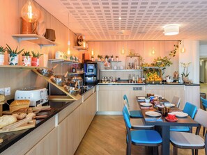 Una cocina moderna con una isla central, electrodomésticos integrados y un comedor con sillas azules.