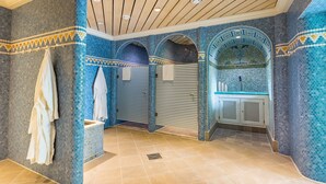 A bathroom with mosaic tile walls, wooden ceiling, and a tiled floor.
