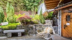 A stone bench, a small waterfall, and a wooden door with a window.