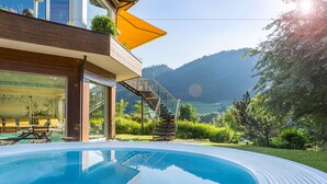 A modern outdoor pool area with a clear view of a mountain and lake.