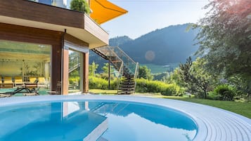 Una piscina techada, una piscina al aire libre, sombrillas