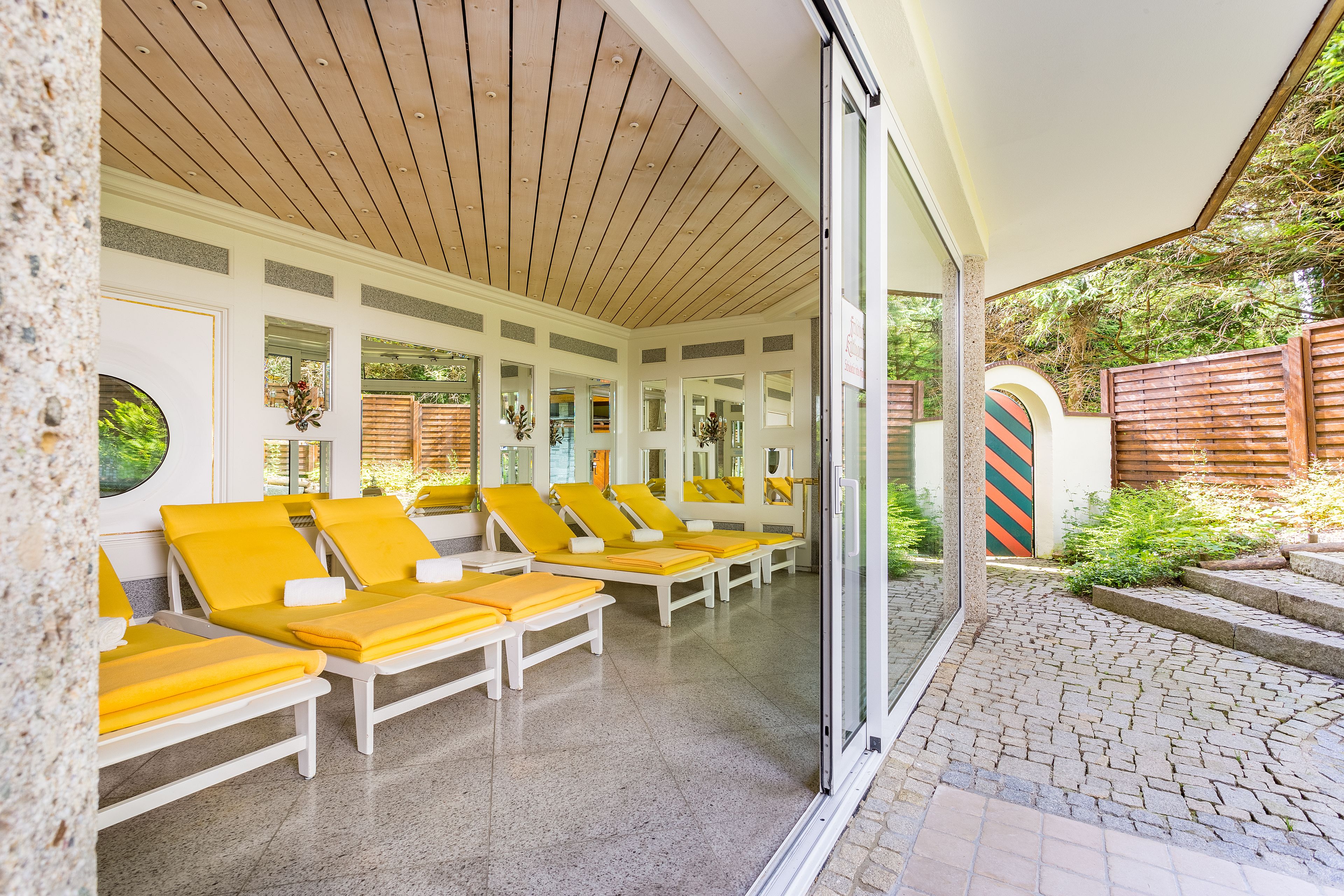 Un espace de détente extérieur, baigné de lumière, avec des fauteuils de couleur jaune et un sol carrelé.