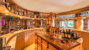 A bar area with a curved wooden counter, shelves with various bottles, and a copper distillation apparatus.