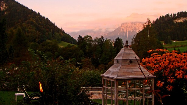 A gazebo in a lush valley with a view of distant mountains.