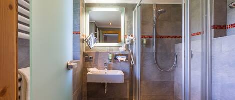 A modern bathroom with a glass-enclosed shower, a sink, and a mirror.