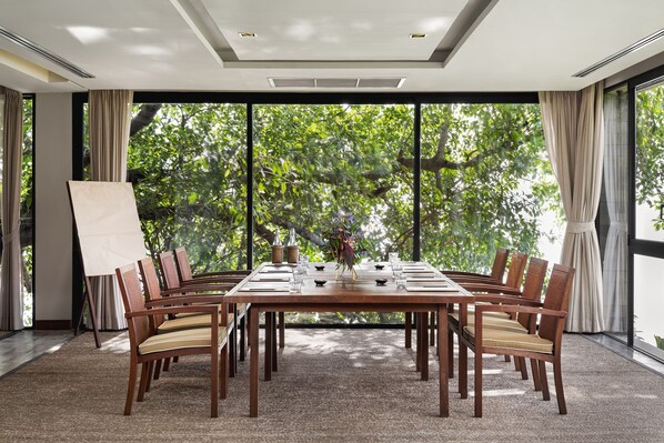 A conference room with a large table, chairs, and a painting on easels.