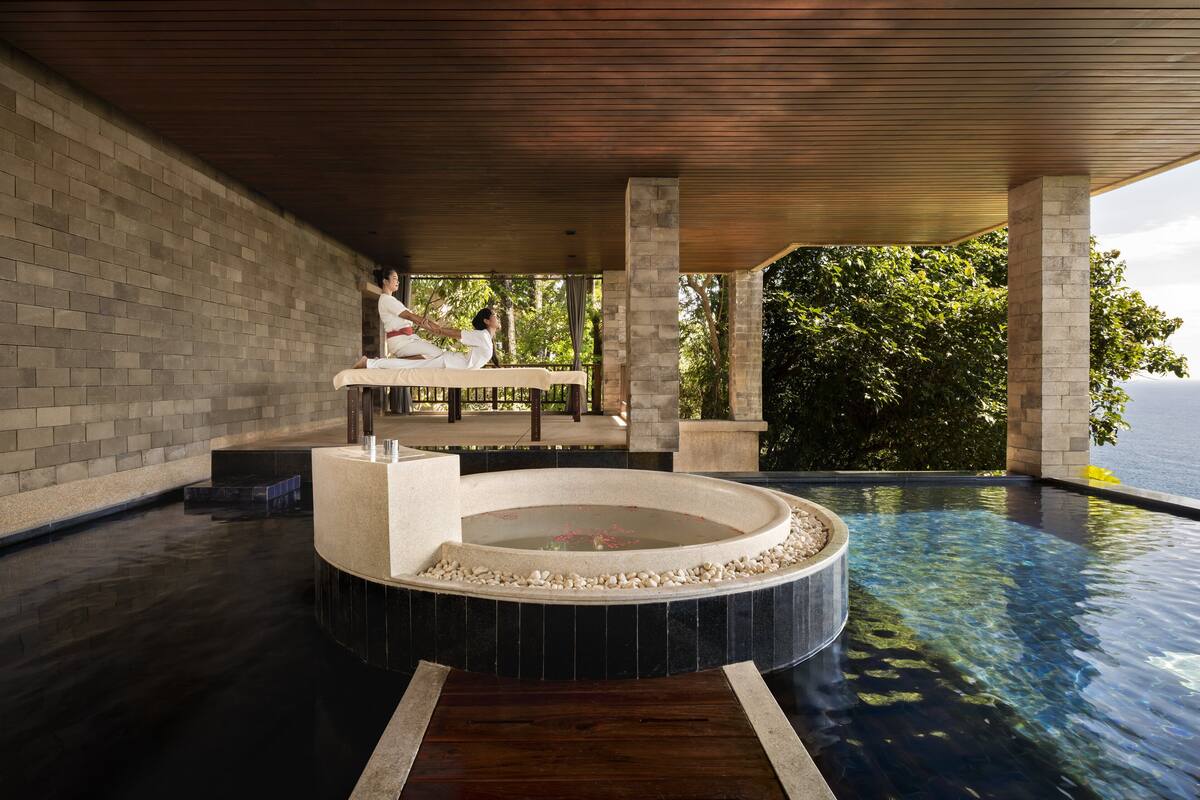 Uma área de spa com uma banheira de hidromassagem circular, teto de madeira e vista para o mar.