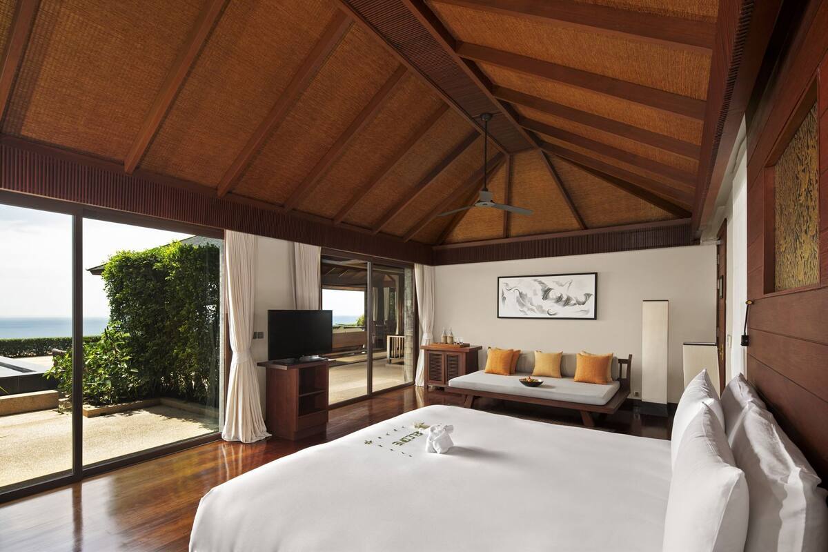 Quarto com cama grande, televisão e vista para o oceano.